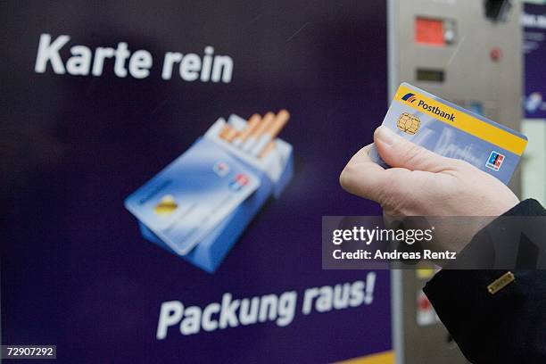 Woman holds her payment card next to a cigarette vending machine December 29, 2006 In Berlin, Germany. Germany?s cigarette vending machines will be...