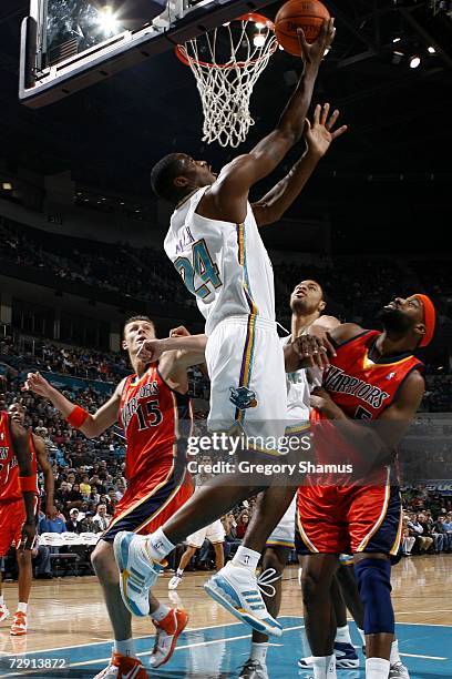 Desmond Mason of the New Orleans/Oklahoma City Hornets gets a shot off between Andris Biedrins and Baron Davis of the Golden State Warriors January...