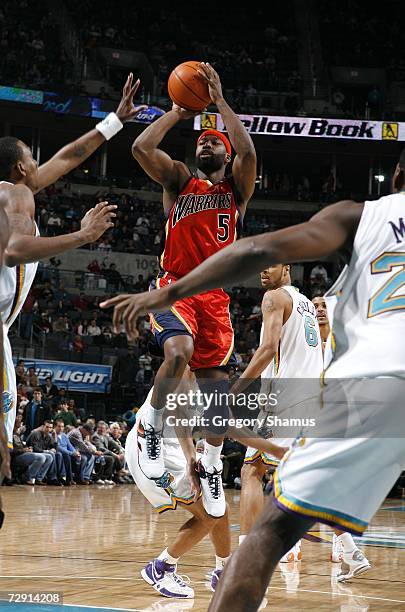 Baron Davis of the Golden State Warriors goes up for a shot between Rasual Butler and Desmond Mason of the New Orleans/Oklahoma City Hornets in NBA...