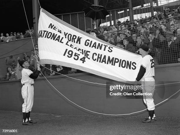 Alvin Dark and Whitey Lockman raise the 1954 pennant prior to the Opening Day game on April 14, 1955 against the Brooklyn Dodgers at the Polo Grounds...