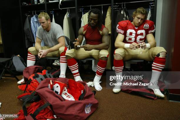 Billy Bajema, Vernon Davis and Eric Johnson of the San Francisco 49ers react in the locker room after the game against the Arizona Cardinals at...