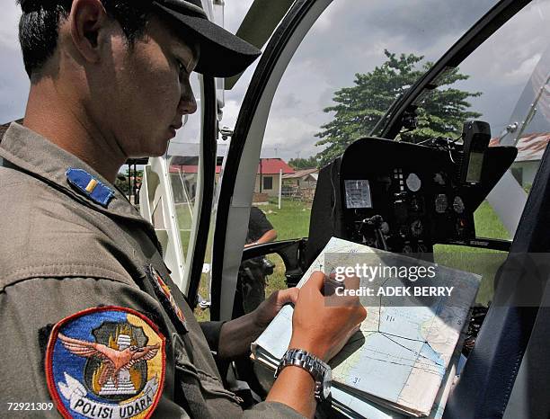 An Indonesian policeman checks a map as search and rescue teams are ongoing in their search for the missing Adam air plane in Polewali, 04 January...
