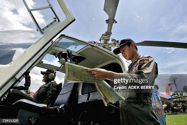 An Indonesian policeman checks a map as search and rescue teams are ongoing in their search for the missing Adam air plane in Polewali, 04 January...