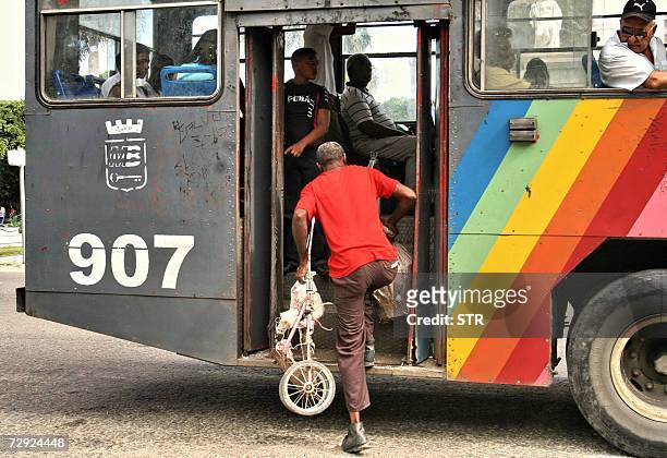 Un cubano aborda un "camello" -autobus inventado en Cuba en los anos 90 para sortear una crisis de transporte, llamado asi por su forma irregular-,...