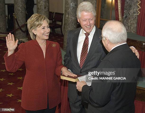 Washington, UNITED STATES: Former US President Bill Clinton, , holds a bible as his wife US Senator Hillary Clinton, D-NY is sworn in today as member...