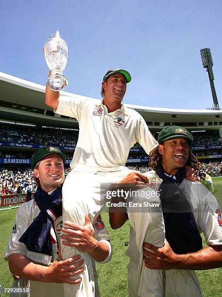 Shane Warne of Australia celebrates on the shoulders of Michael Clarke and Andrew Symonds with the Ashes trophy after winning the final test and...