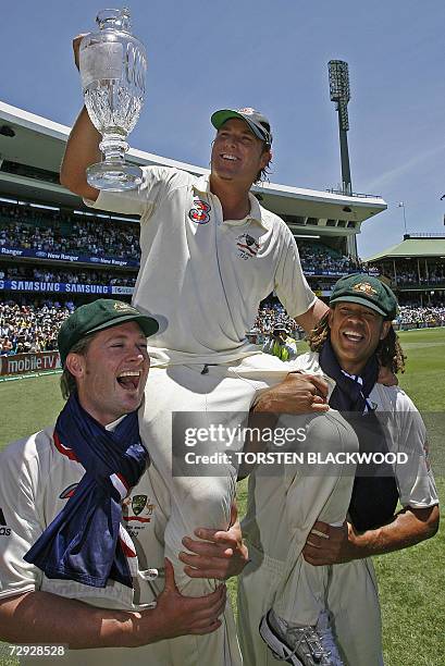 Retiring spin bowler Shane Warne holds The Ashes trophy aloft as he is carried by team-mates Michael Clarke and Andrew Symonds on a farewell victory...