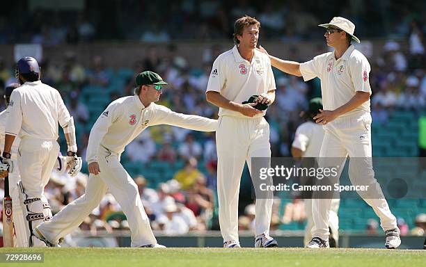 Glenn McGrath of Australia is congratulated by team mates Michael Clarke and Stuart Clark after taking the wicket of Kevin Pietersen of England...