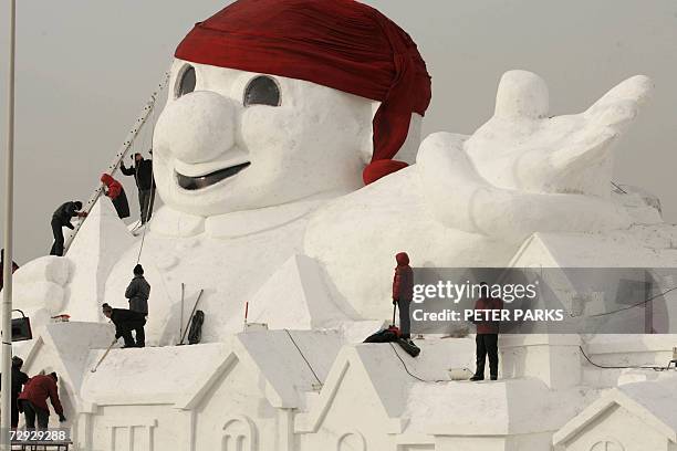 Workers puts the finishing touches to a giant snowman at a snow and ice exhibition in the northern Chinese city of Harbin 05 January 2007. As...