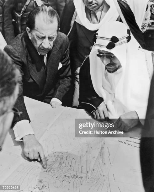 American oil magnate J. Paul Getty points out the town of Al Wafrah on a map of southern Kuwait to King Saud bin Abdul Aziz of Saudi Arabia , 1954.