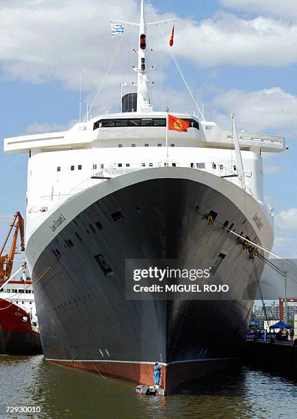 Picture taken 06 November 2003 shows a painter working on the hull of the passenger vessel "Queen Elizabeth 2" docked at Montevideo's harbor. The...