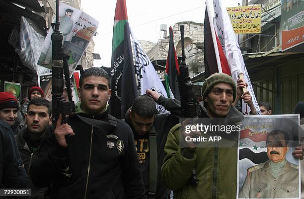 Palestinian militants from the al-Aqsa Martyrs Brigades, an armed offshoot of the Fath party, tot their rifles and hold a poster of executed former...