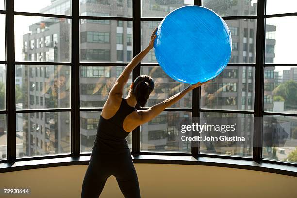 woman using exercise ball in empty apartment - fitness ball stock pictures, royalty-free photos & images