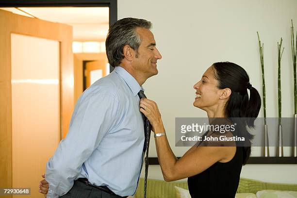 woman adjusting husband's tie at home - adjusting necktie stockfoto's en -beelden
