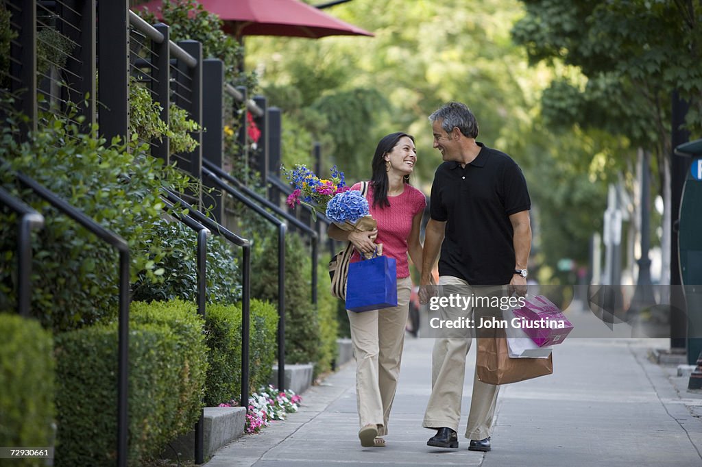 Couple with shopping bags, walking on sidewalk