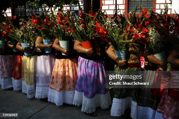 Women carry flowers during a regada ceremony in Juchitan, Mexico, June 5, 2003. Whether it is a religious ceremony or an Indian celebration, every...
