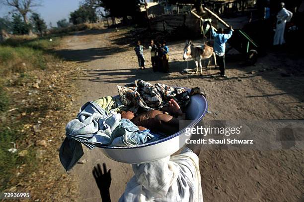 Senegalese woman carries her baby on her head in the rural village of Dialakoto, Senegal, August 23, 2001. In Senegal, rural communities including...