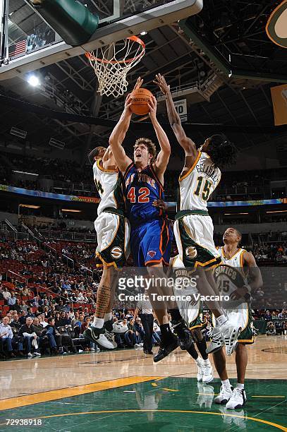 David Lee of the New York Knicks goes to the basket between the defense of Andre Brown and Mickael Gelable of the Seattle SuperSonics on January 5,...