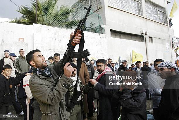 Palestinian Fatah supporter fires a gun in celebration over the crowd during a rally to mark the 42nd anniversary of the political party on January...
