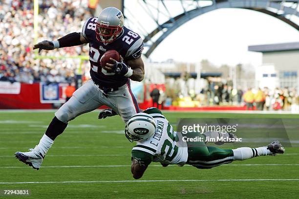 Corey Dillon of the New England Patriots runs with the ball as Erik Coleman of the New York Jets tries to tackle him during the AFC Wild Card Playoff...