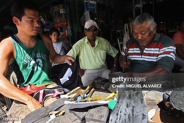 Dos zapateros arreglan calzado en su taller en Managua, el 07 enero de 2007. Miles de nicaraguenses que viven en la pobreza esperan que el gobierno...
