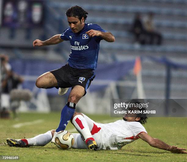 Dubai, UNITED ARAB EMIRATES: Iran's national football team player Amir Hossen Sadeghi falls on the ground as he figths for the ball with Hamburg's...