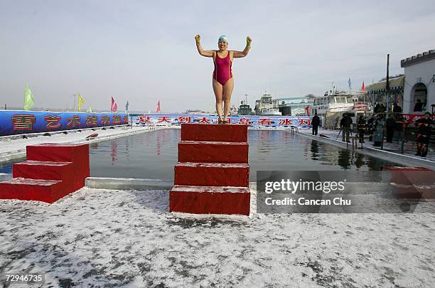 Winter swimming performer waves to tourists before diving into a pool carved out of the frozen Songhua river during the 23rd Harbin International Ice...