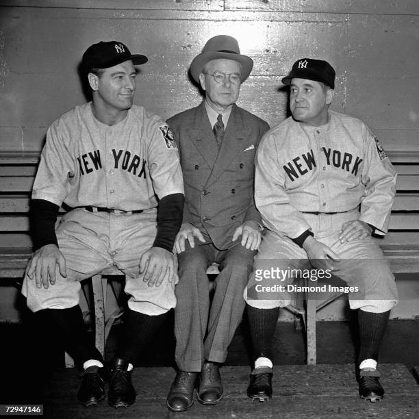 Firstbaseman Lou Gehrig, of the New York Yankees, John Hillerich, of Hillerich and Bradsby and Yankees' manager Joe McCarthy pose on the bench prior...