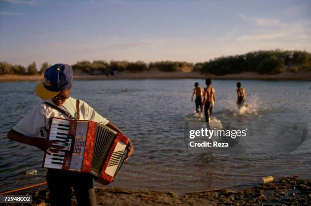 Schoolgirl plays the accordion during a picnic by Ein Dabban lake in May 2000 in Libya.