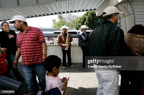 Musicians perform while Pedestrians wait in line to enter the United States at the border in Tijuana Mexico from the United States January 8, 2007 in...