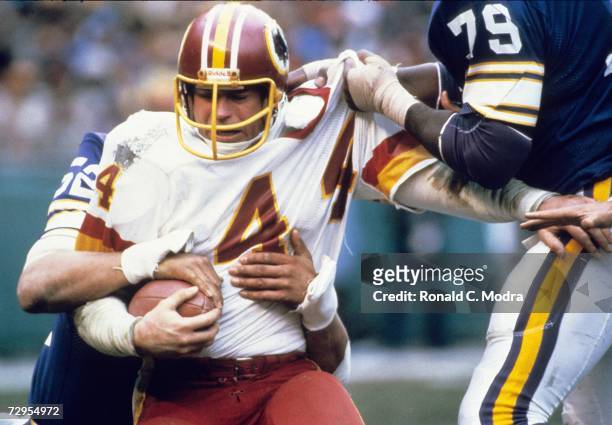 John Riggins of the Washington Redskins carries the ball as Doug Martin of the Minnesota Vikings grabs his jersey during the NFC Divisional Playoff...