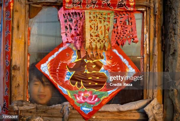 Girl looks through the window of her house, decorated traditionally for Chinese New Year on February, 1999 in Mohe, China.