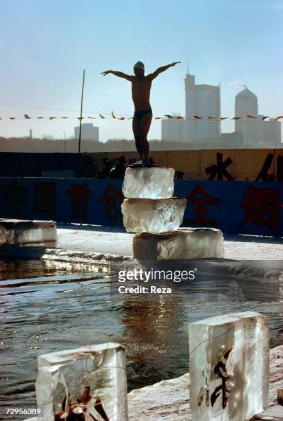 Man belonging to a local association of swimmers in icy waters is about to jump from a diving board sculpted in ice, into a swimming pool, with a...