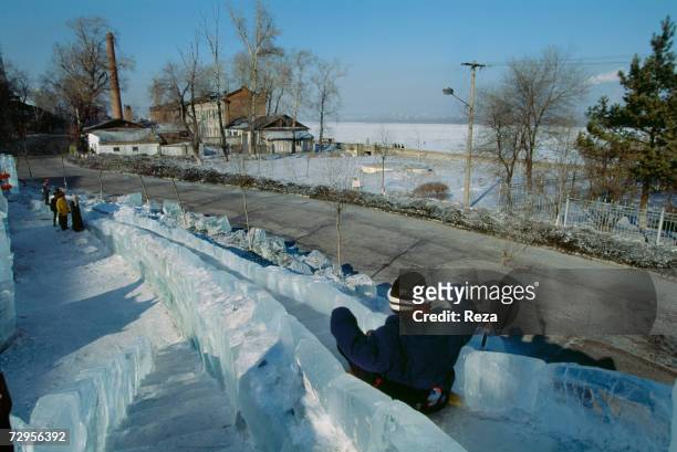 Child plays on a slide, made with blocks of ice, by the Amur River on February, 1999 in Heihe, China.
