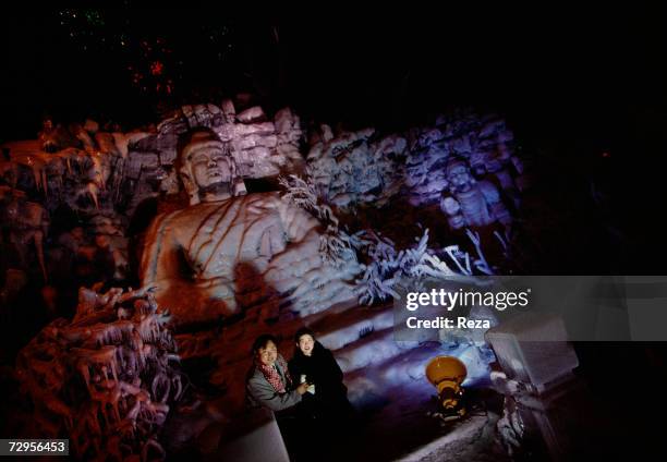 When night falls, visitors are being photographed in front of a huge illuminated ice sculpture representing a Buddha, in Sun Island Park during the...