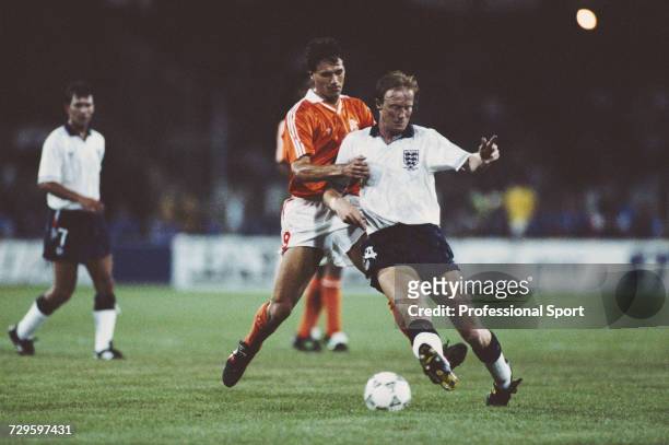 English footballer Mark Wright is tackled by Marco van Basten of the Netherlands as England captain Bryan Robson looks on, in the Group F match...