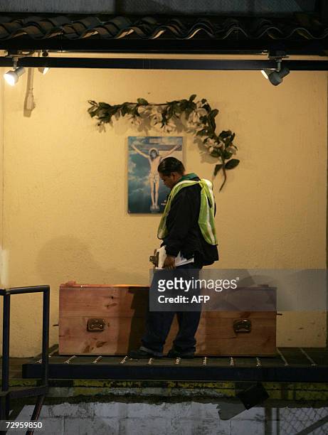 Guatemala City, GUATEMALA: An airport worker observes the coffin bearing the remains of ten-year-old Sergio Pelico 09 January 2007 in Guatemala City,...