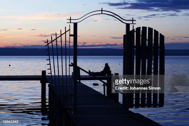 Man sits on a dock during a very mild winter evening at the beach of Ammersee Lake on January 10, 2007 in Herrsching, Germany. Bavaria and most parts...