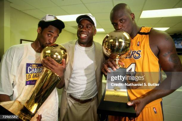 Shaquille O'Neal and Kobe Bryant of the Los Angeles Lakers pose with Lakers legend Magic Johnson after winning the NBA Championship trophy after...