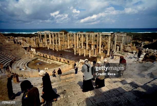 Veiled women stand on the tiered seating area of the Roman theater overlooking the ocean, part of the ruins of Leptis Magna, the largest city of the...