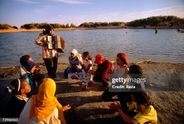Schoolgirl plays the accordion during a picnic on March, 2000 in Ein Dabban lake, Libya.