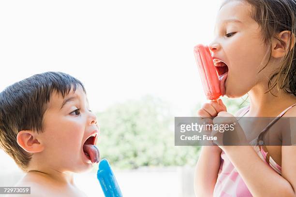 brother and sister licking popsicles - child eat side photos et images de collection