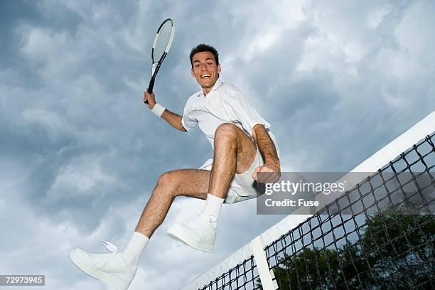 tennis player jumping over tennis net - shorts down stock pictures, royalty-free photos & images