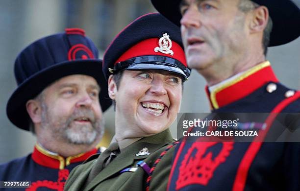 London, UNITED KINGDOM: Moira Cameron smiles in her British Army uniform as she is flanked by Beefeater Warders, Chief Yeoman Warder, John Keohane...