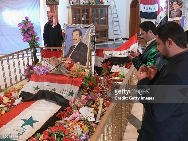 Iraqi men pray at the grave of Iraq?s former President Saddam Hussein on January 11, 2007 in his home town Awja in Tikirt province 80 miles north of...