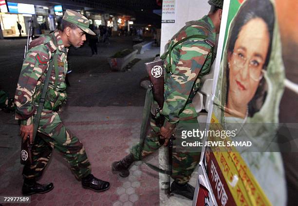 Bangladeshi military soldiers walk towards their makeshift camp passing a poster of opposition leader Sheikh Hasina Wajed following their deployment...