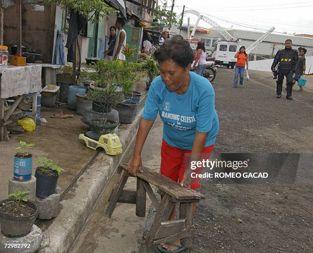 Squatter resident Dulce Becera carries a chair for her store near the Cebu International Convention Center, seen in the background at right 12...