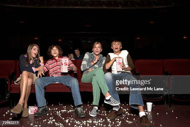 four teenagers sitting in movie theatre auditorium - girlfriends films stockfoto's en -beelden