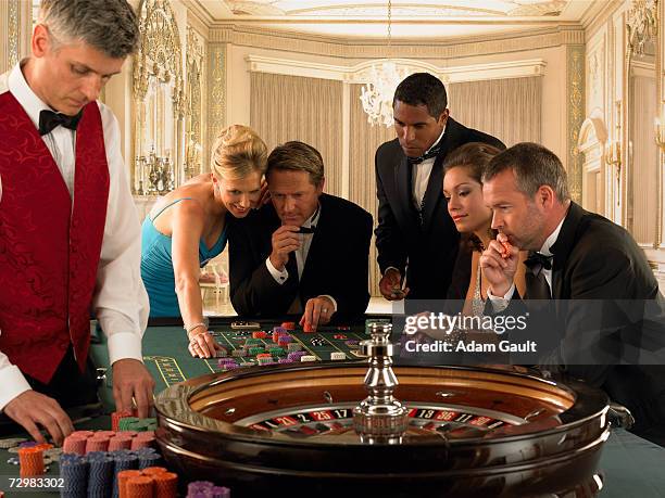 five people gambling beside croupier at roulette table - casino dealer stockfoto's en -beelden