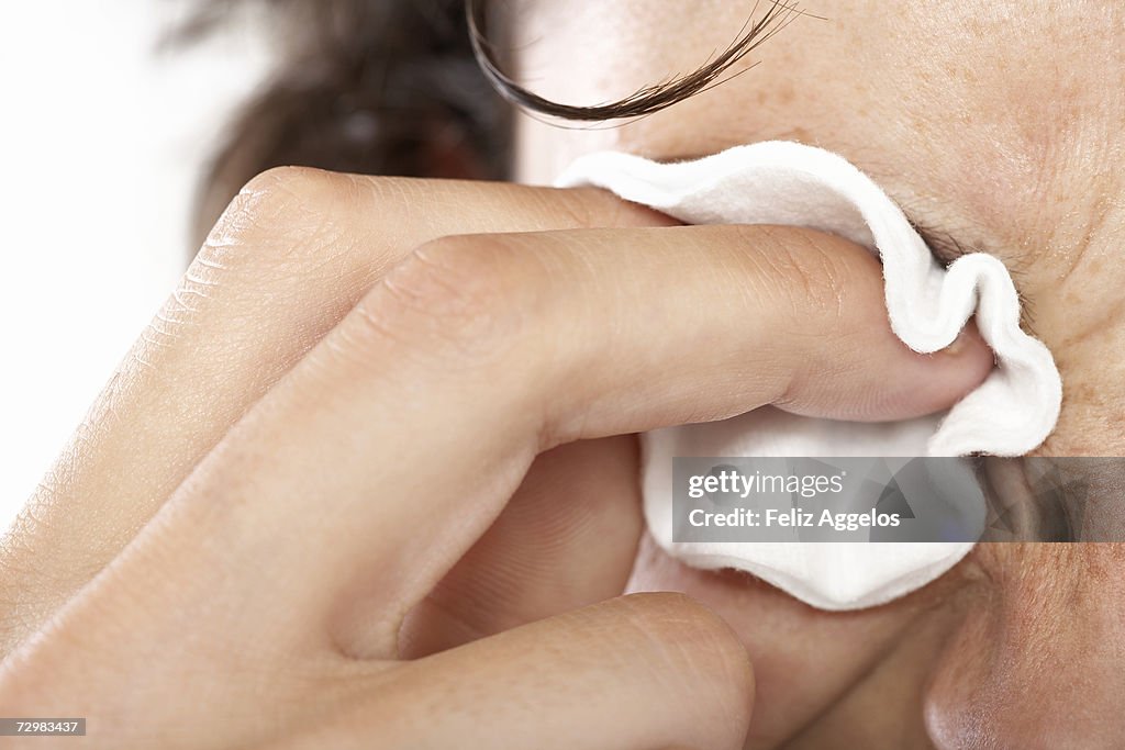 Woman removing make-up with cotton pad, close-up